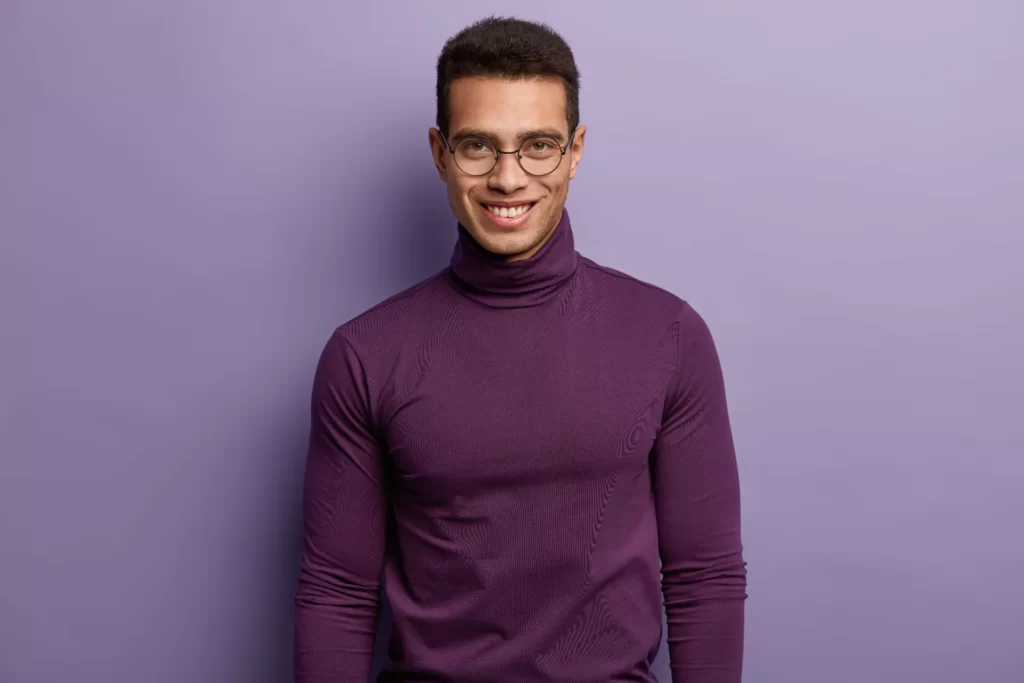 smiling man wearing round glasses and purple turtl utc